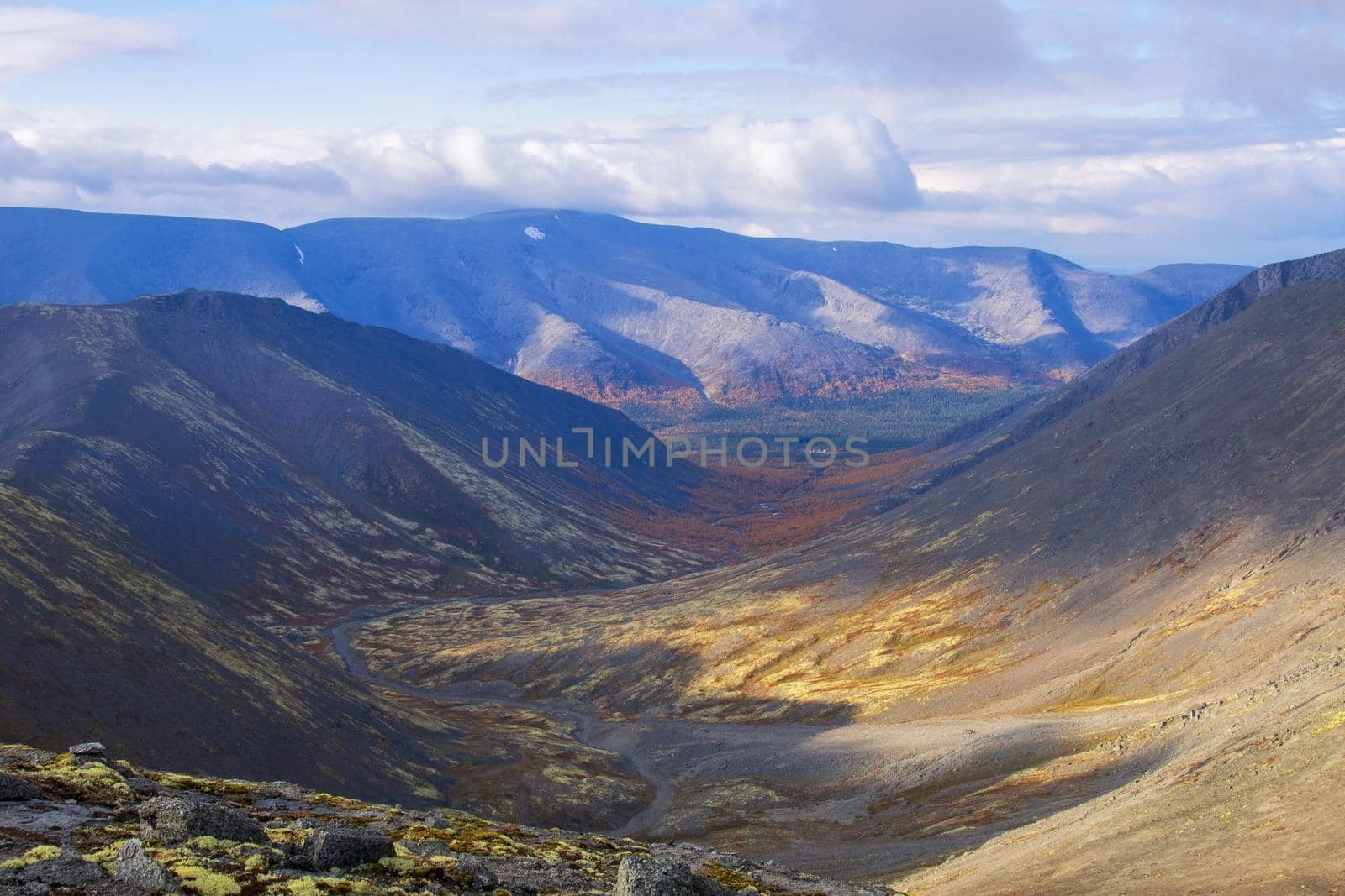 Autumn colorful tundra on the background mountain peaks in cloudy weather. Mountain landscape in Kola Peninsula, Arctic, Khibiny Mountains.