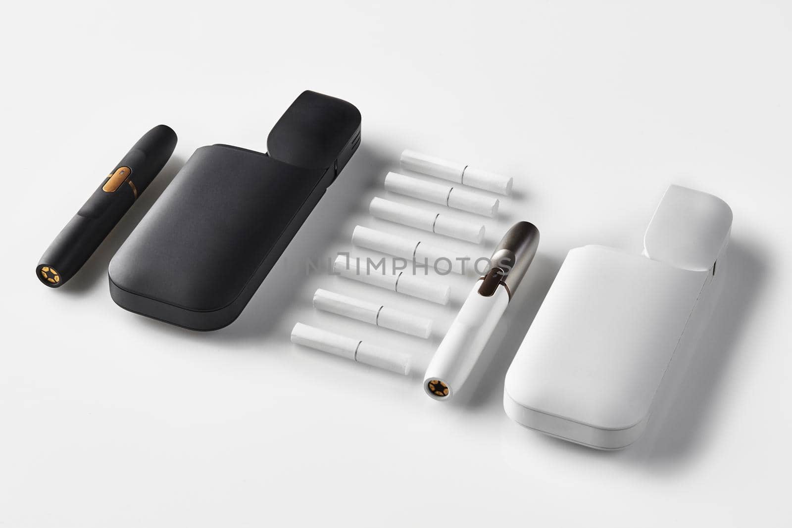 New generation, black and white, two electronic cigarettes and two open batteries, seven heatsticks isolated on white. Heating tobacco system. Tools used to help stop smoking. Close up, copy space