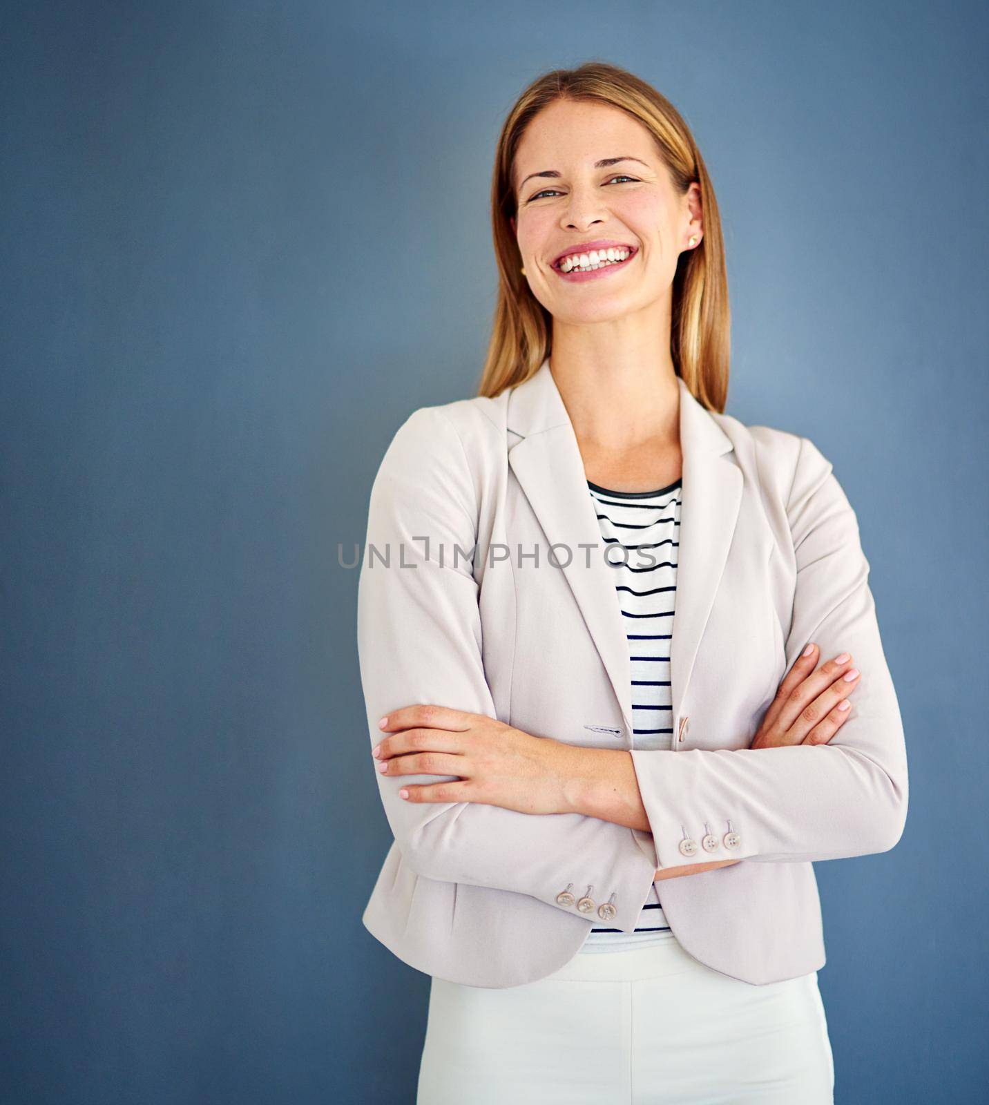 Dress how you want to be addressed. Shot of a woman dressed in office-wear posing against a blue background. by YuriArcurs