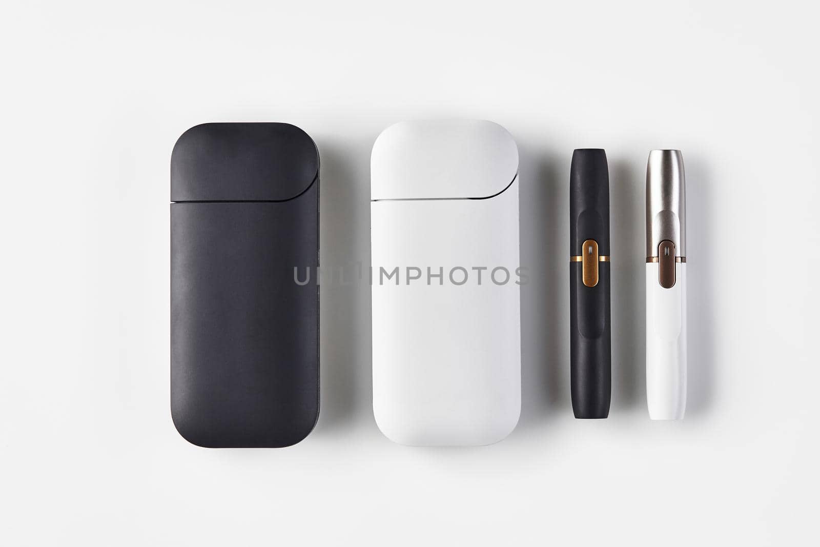 New generation black, white and silver electronic cigarettes and batteries isolated on white. Hi-tech heating tobacco system. Tools used to help stop smoking. Close up, copy space, flat lay