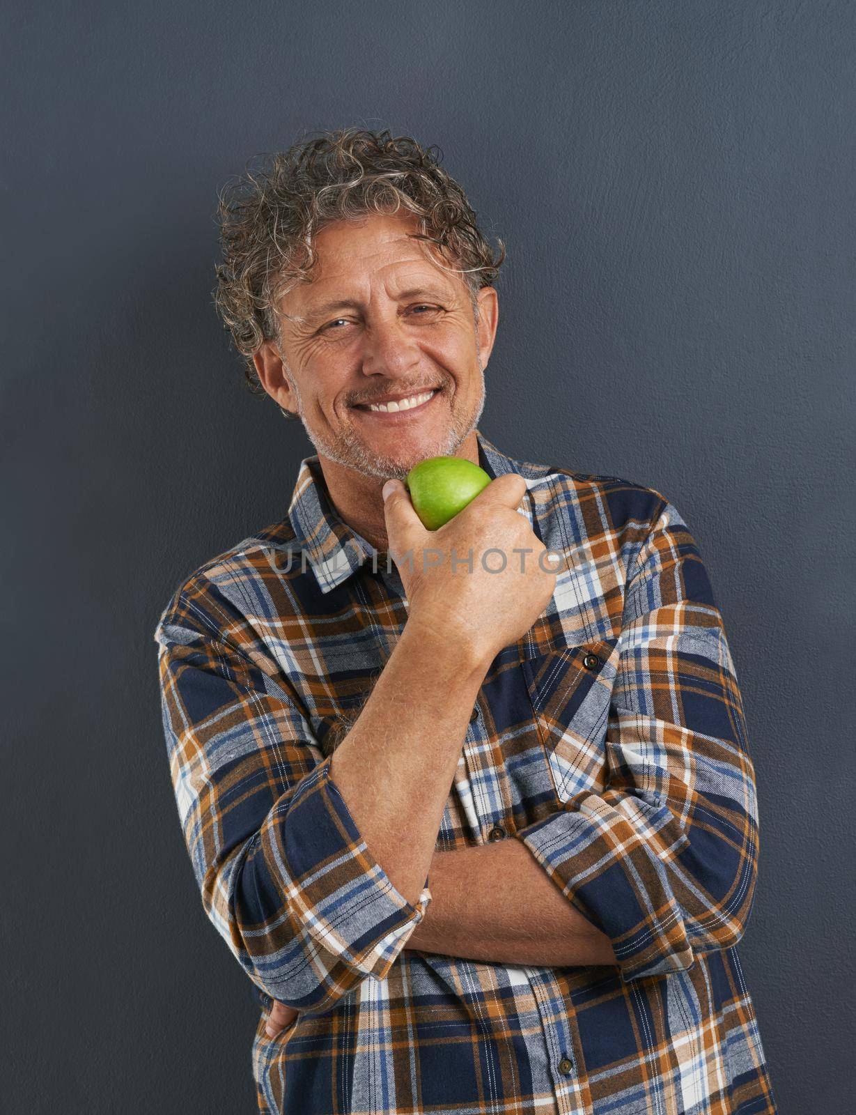 A portrait of a happy mature man holding a delicious apple.