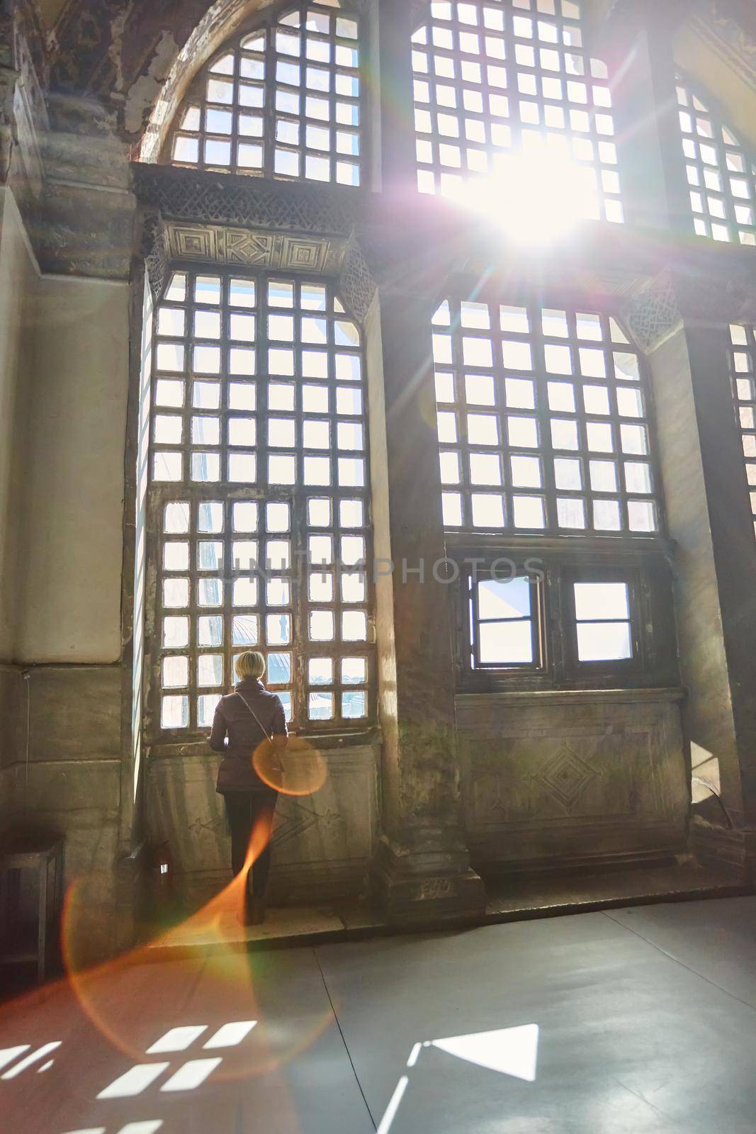 Silhouette of a woman on the window. Haze and sunlight beam.