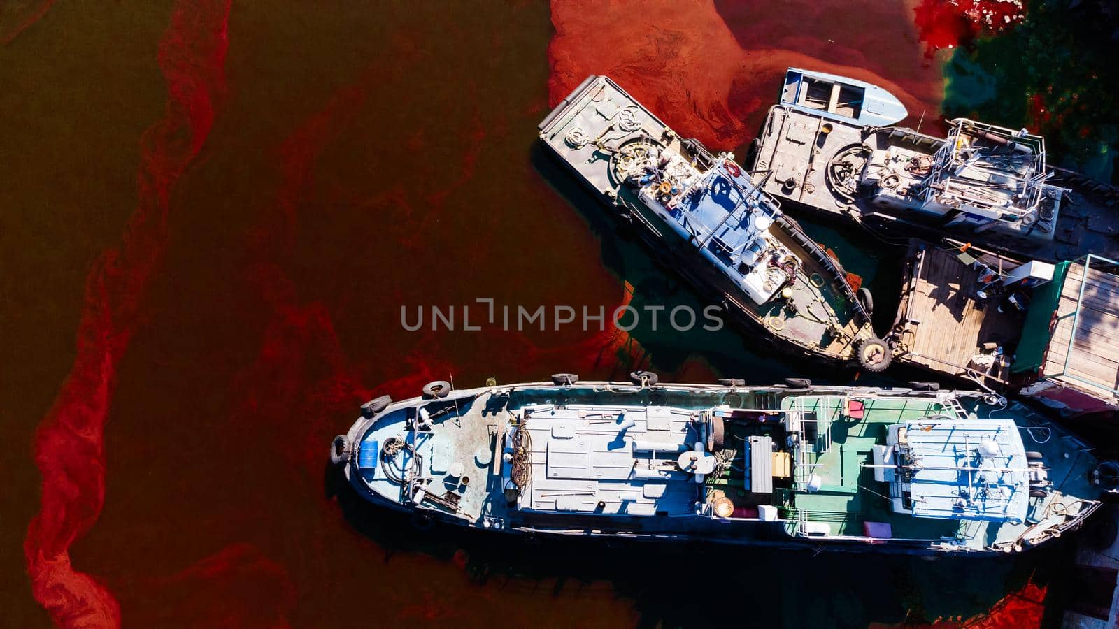 An old rusty red and brown barge in red water. Urban and industrial decay concept