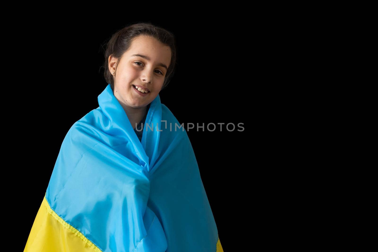 Little girl with Ukrainian flag on dark background.