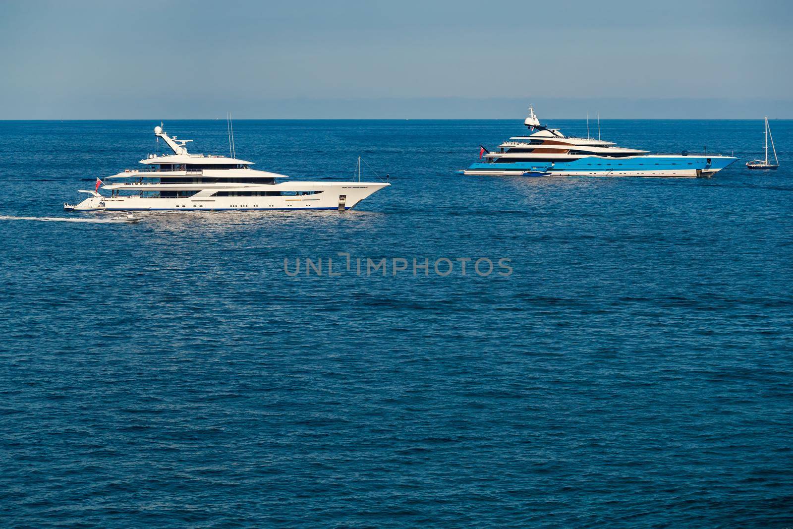 The two huge mega yachts are moored in sea at sunny day, the chrome plated handrail, sun reflection on glossy board of the motor boat. High quality photo