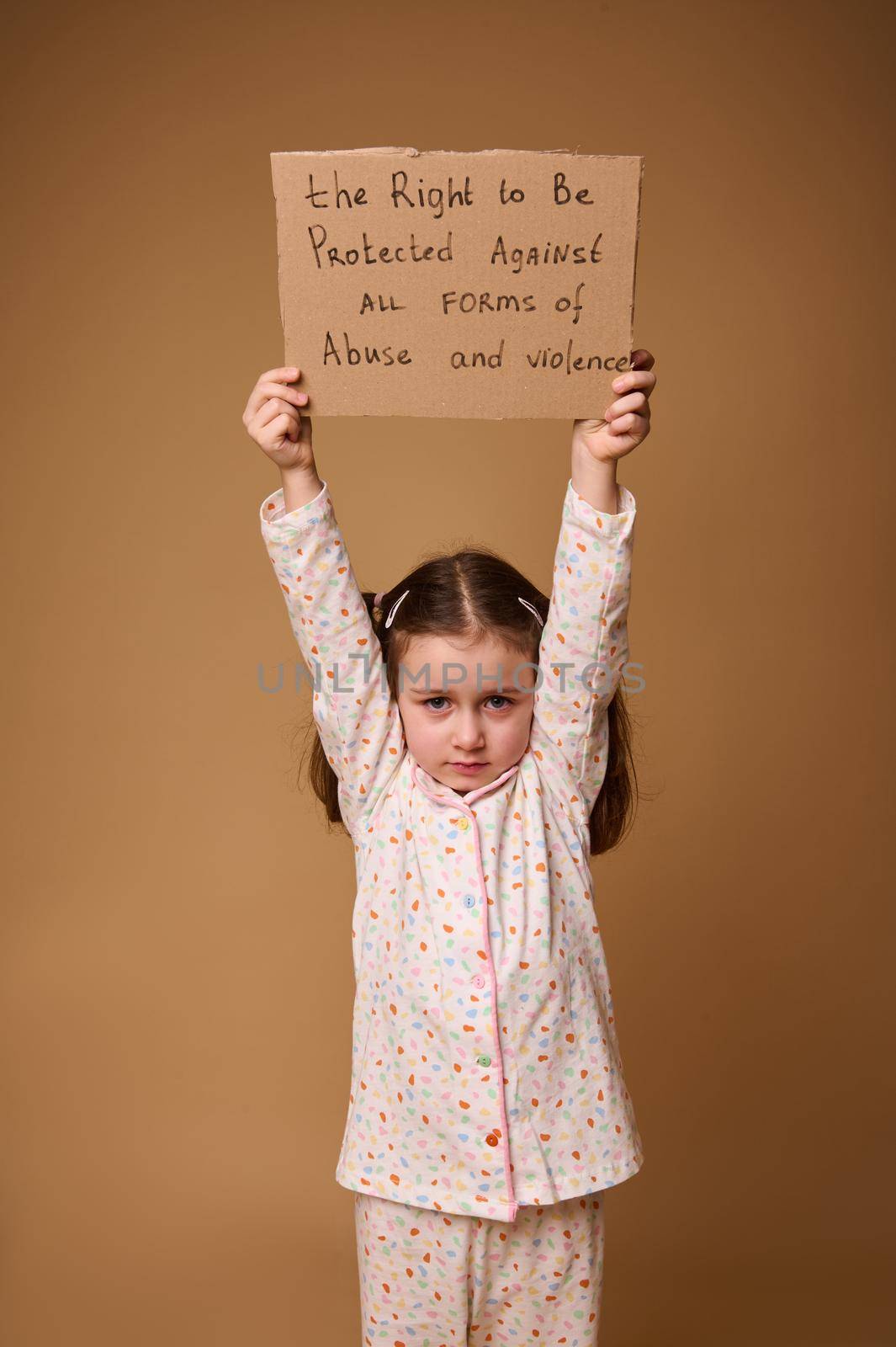 Conceptual studio shot for International Children's Day. Child with advertising banner calling for protection of the rights of children, to protect kids against violence and abuse by artgf