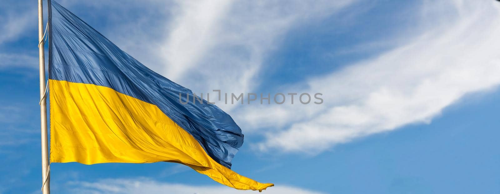 Large national flag of Ukraine flies in the blue sky. Big yellow blue Ukrainian state banner. Independence, flag, Constitution Day, National Holiday, text space. by Andelov13