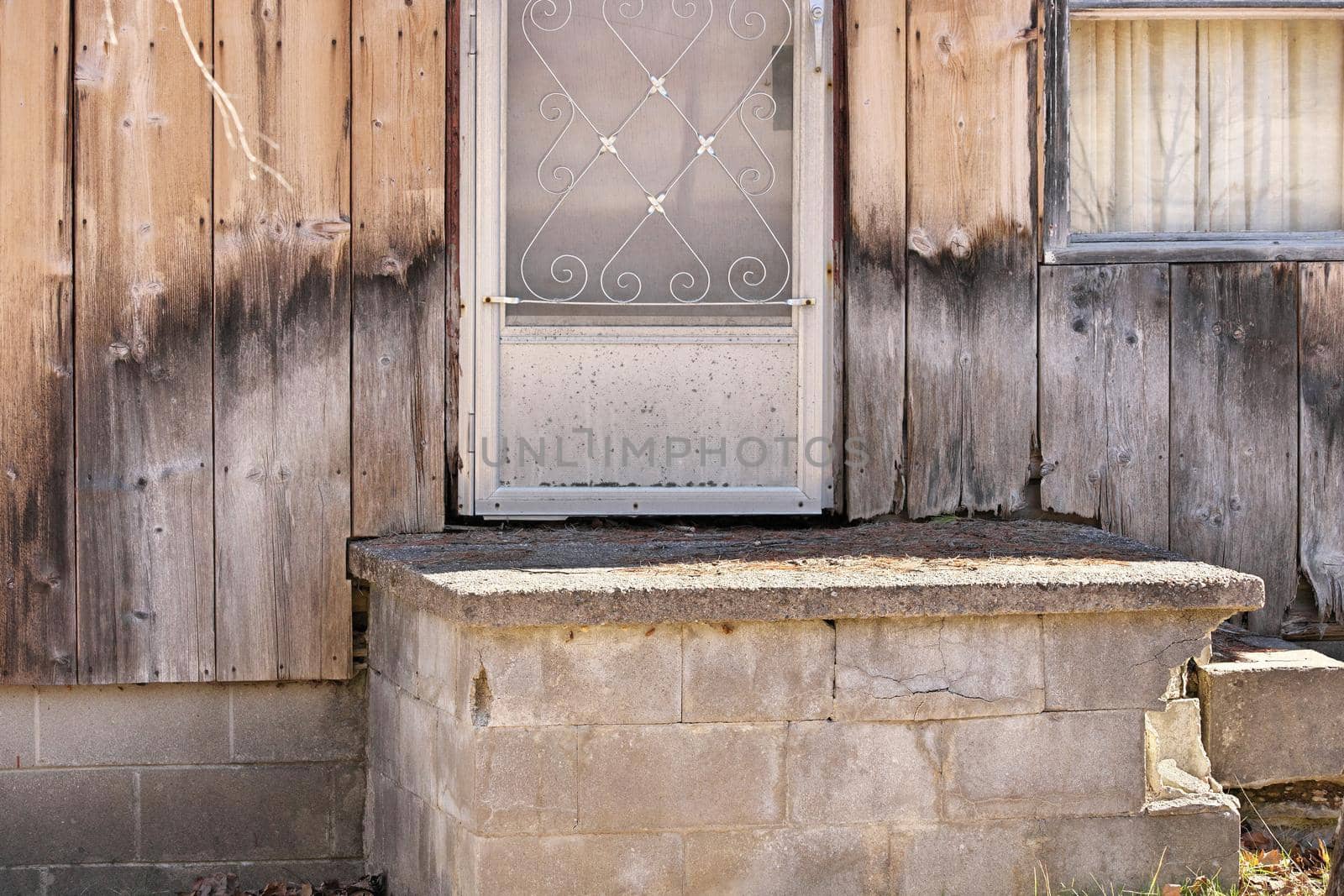 Close up of Weathered Wood Siding Beginning to Rot Around Front Step of Cottage or House by markvandam