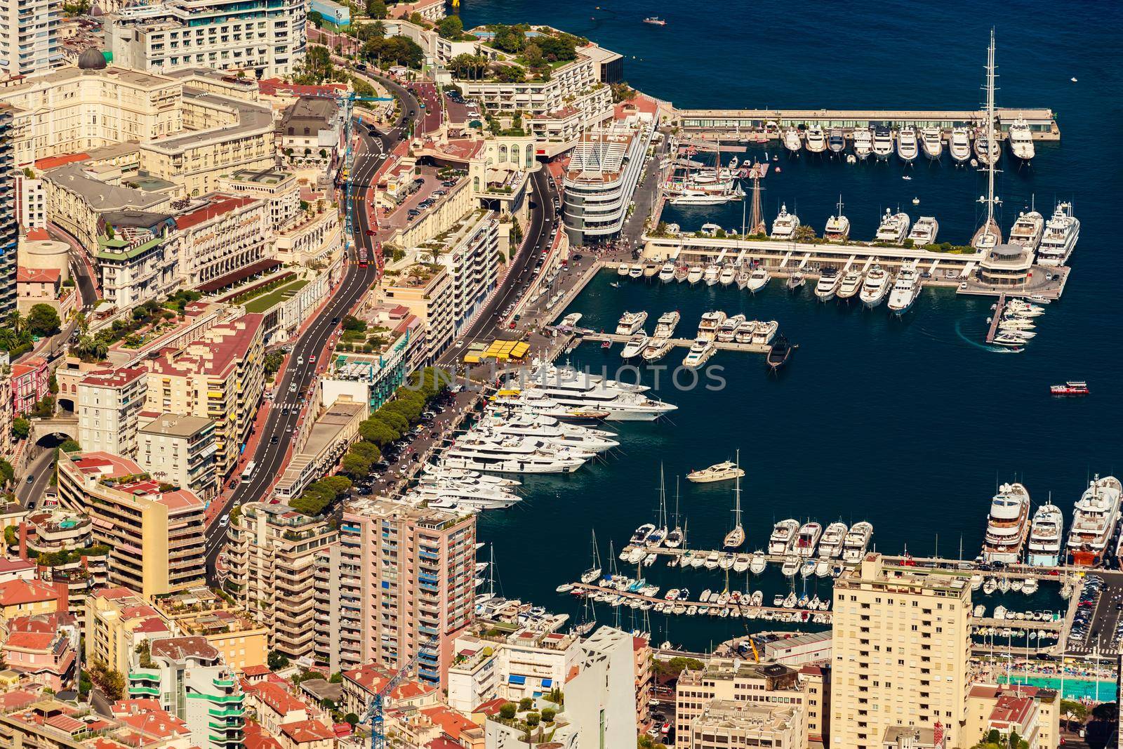 Aerial view of port Hercules of Monaco at sunset, Monte-Carlo, huge cruise ship is moored in marina, view of city life from La Turbie mountain, a lot of mega yachts and boats. High quality photo