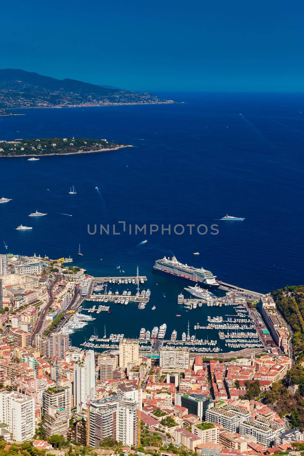 Aerial view of port Hercules of Monaco at sunset, Monte-Carlo, huge cruise ship is moored in marina, view of city life from La Turbie mountain, a lot of mega yachts and boats. High quality photo