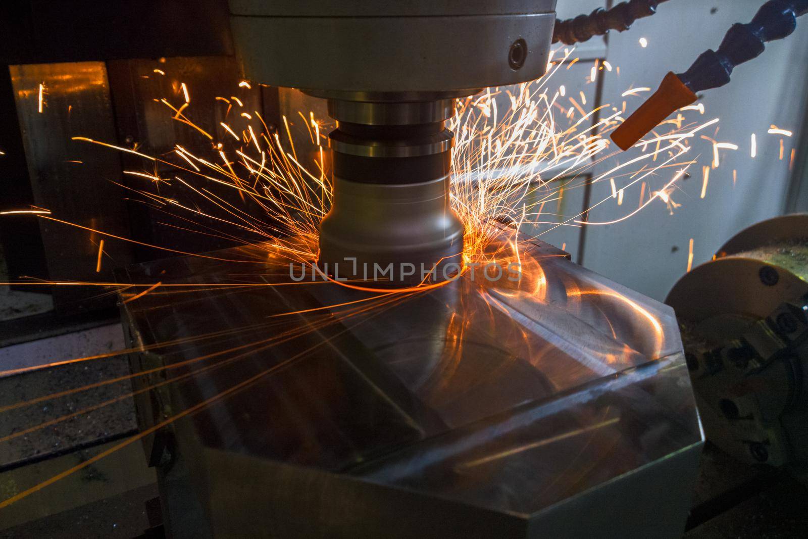 Heavy milling with sparks caused overheating due to wrong cutting feeds and speeds. Safety rules violation in manufacturing process. Selective focus technique in low light conditions.