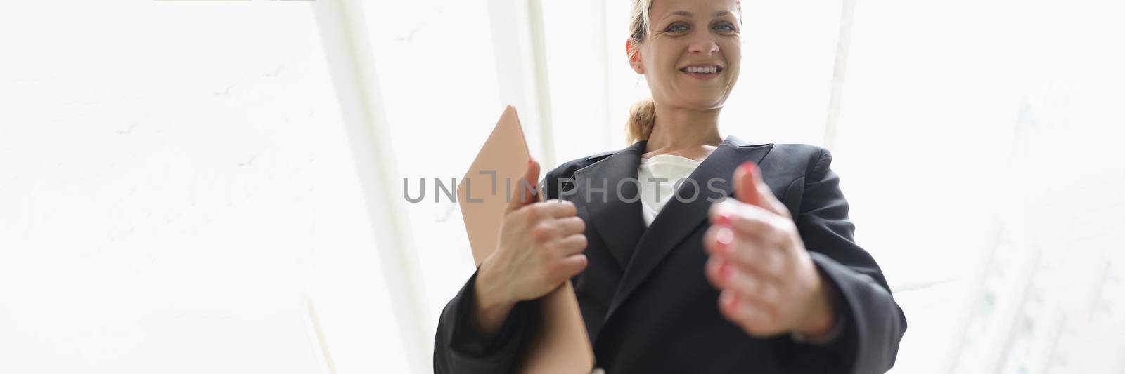 Young woman in business suit stretching out her hand for handshake bottom view. Successful business deal concept