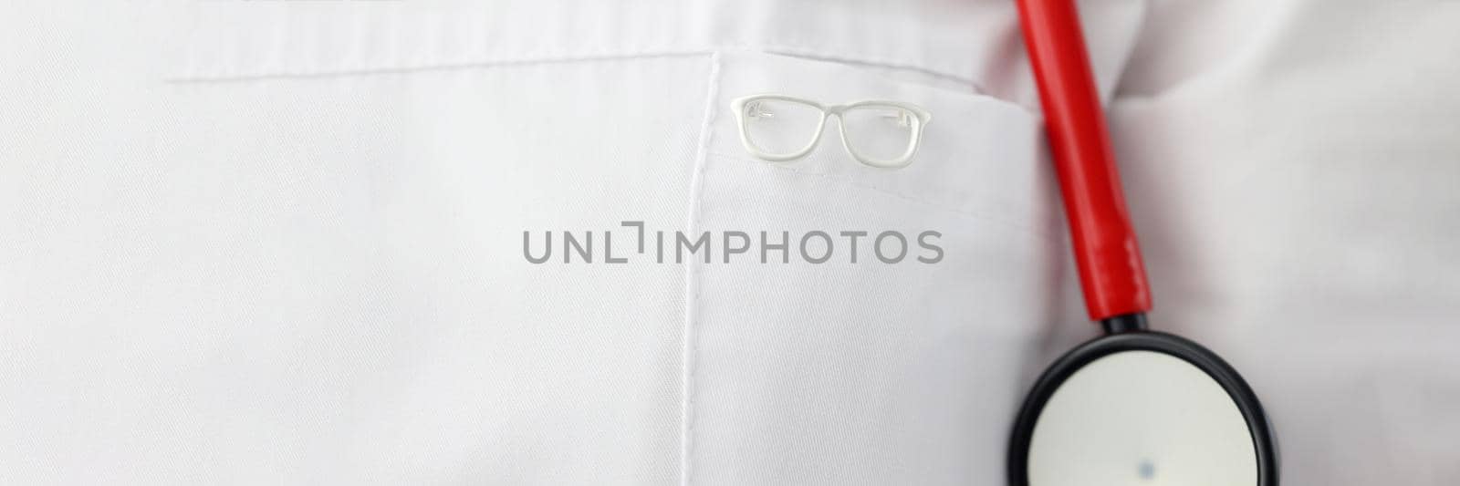 Eyeglass shape icon hanging on ophthalmologist gown closeup by kuprevich