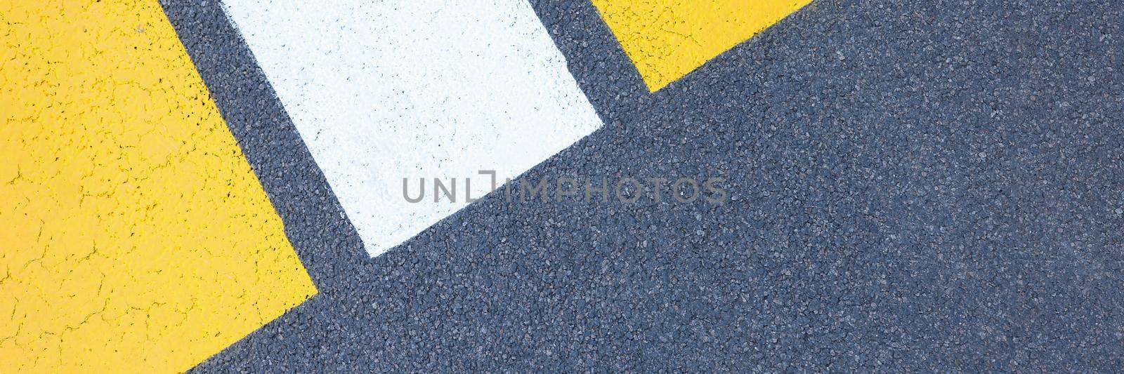 Closeup of yellow and white stripes on gray asphalt background. Traffic laws concept