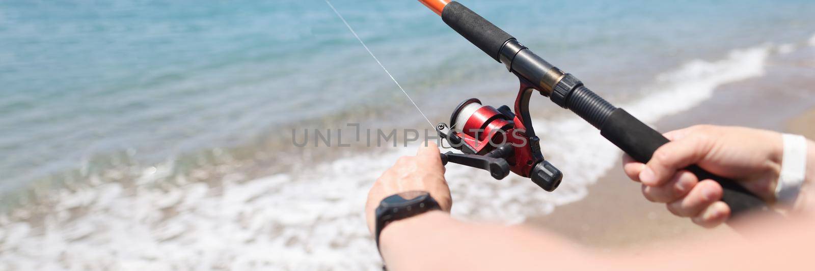 Man fishing with rod on seashore closeup. Men hobby fishing concept