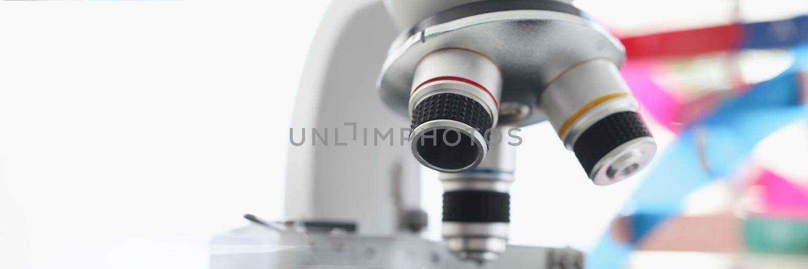 Microscope standing near multicolored model of dna chain in lab by kuprevich