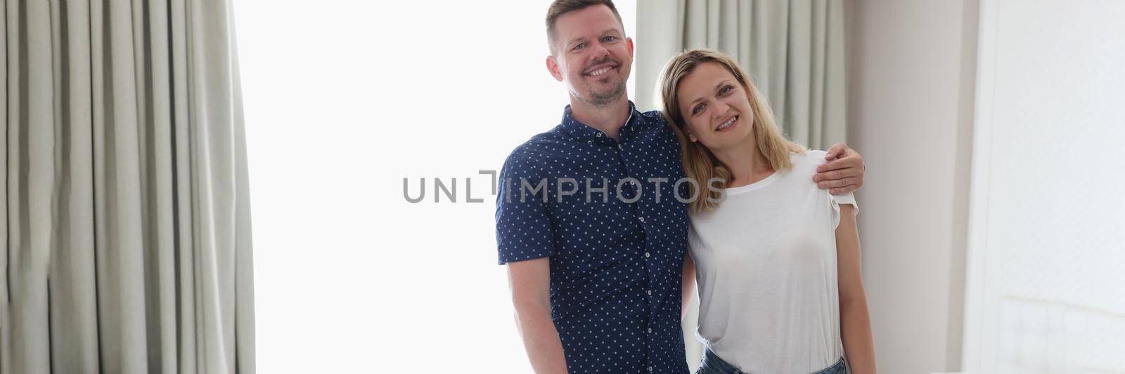 Young couple standing with suitcase in hotel room. Honeymoon concept