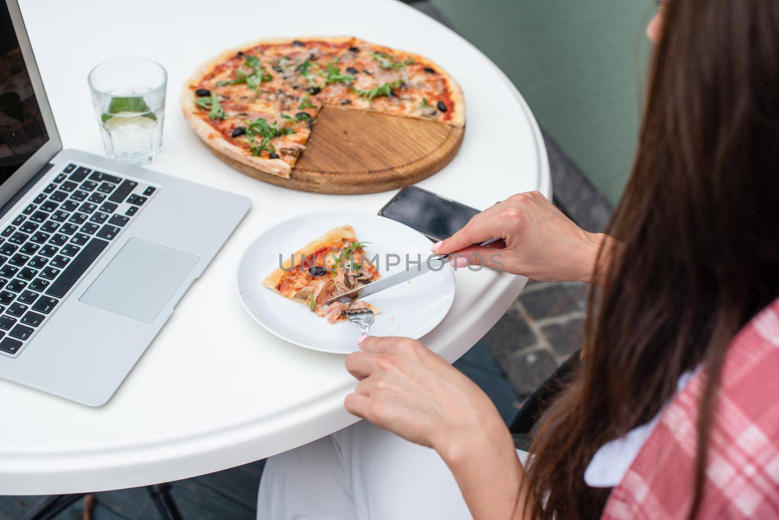 Top view of business woman eating pizza while working at a pizza restaurant by Ashtray25