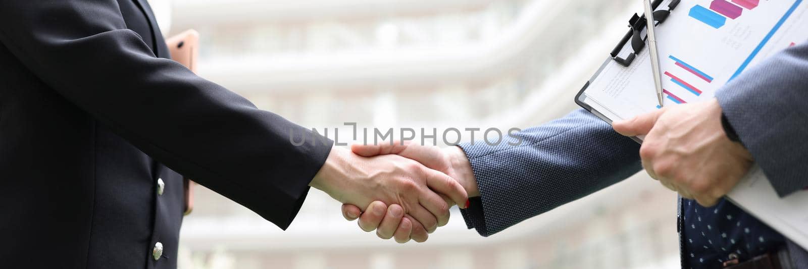 Business man and woman with documents shaking hands closeup by kuprevich