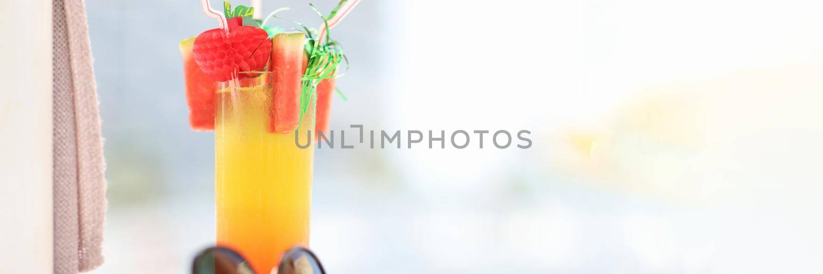 Sunglasses lying near alcoholic cocktail glass on beach closeup. Vacation at resort concept