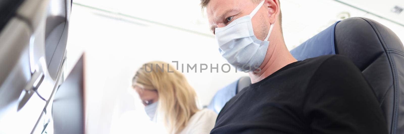 Man and woman in protective masks working on laptops in aircraft cabin by kuprevich