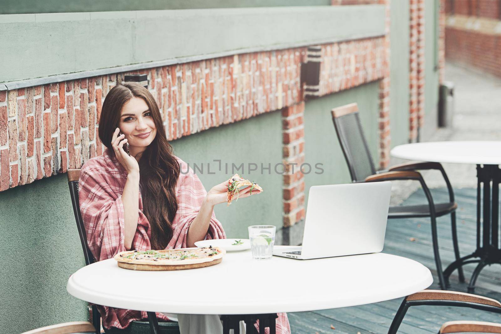 Young freelancer woman using laptop computer and eat pizza while sitting at cafe table. Business People Concept