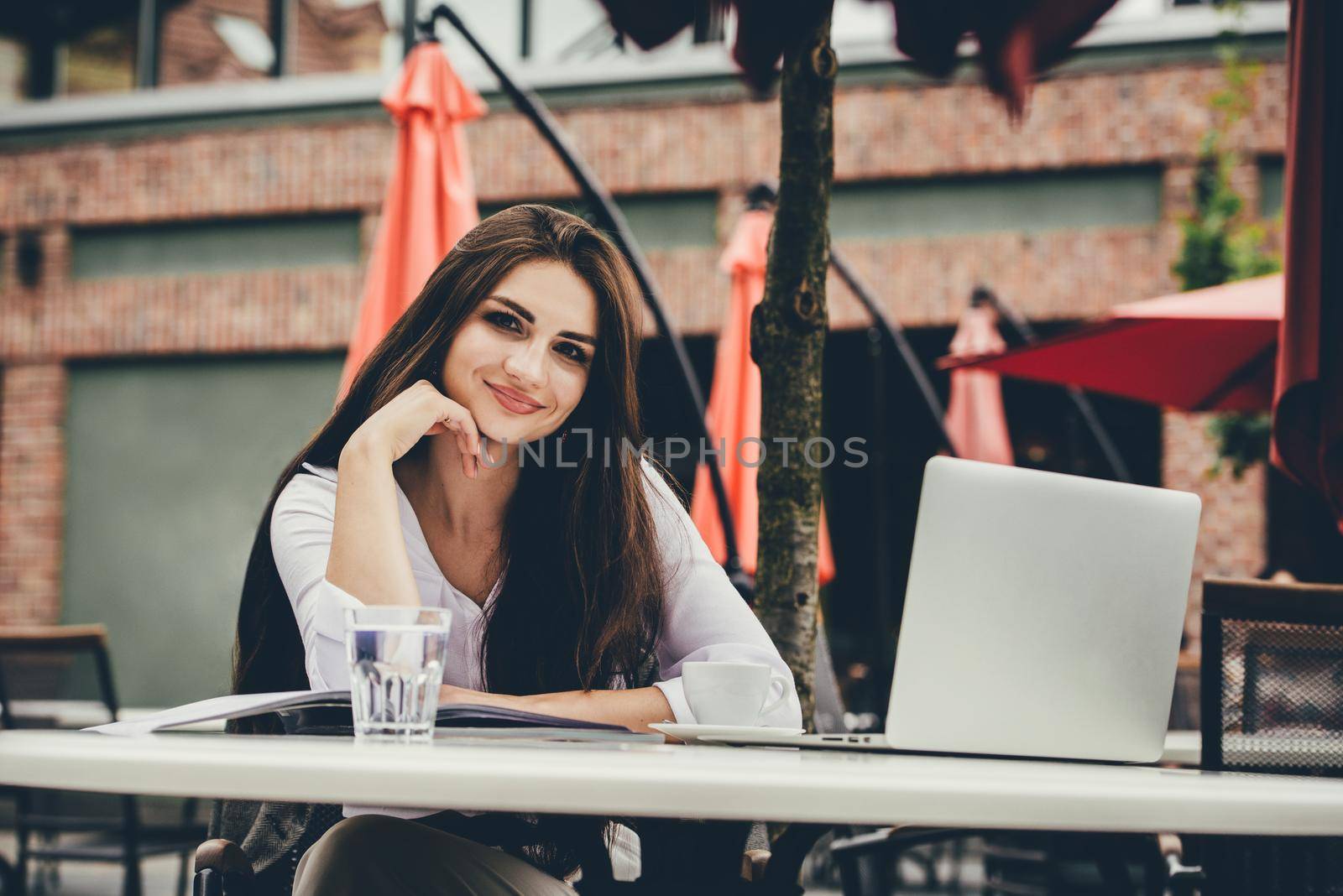 Young freelancer woman using laptop computer sitting at cafe table. Smiling woman working online or studying and learning while using notebook. by Ashtray25