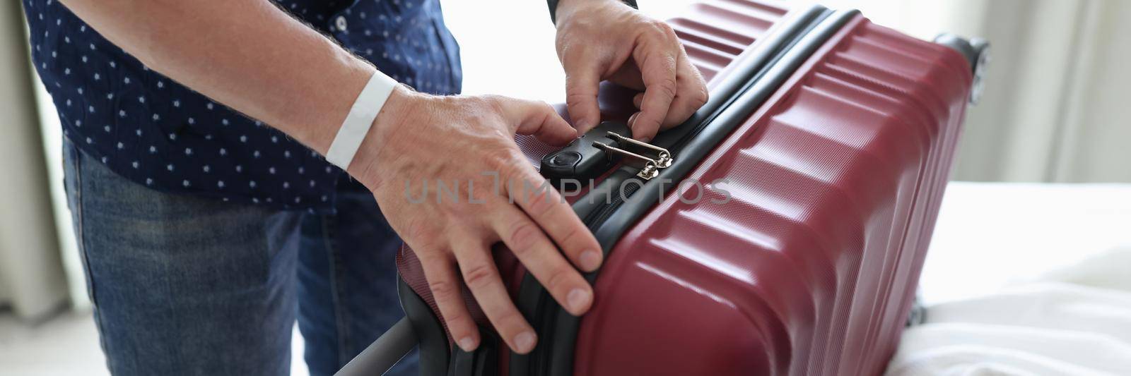 Man closing suitcase with combination lock at home closeup by kuprevich