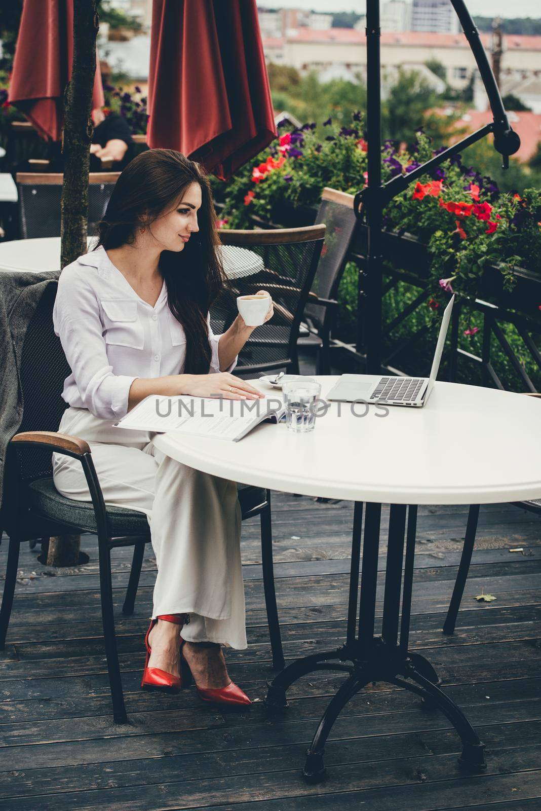 Young brunette woman using laptop computer sitting at cafe table and drik coffe. . Business People Concept