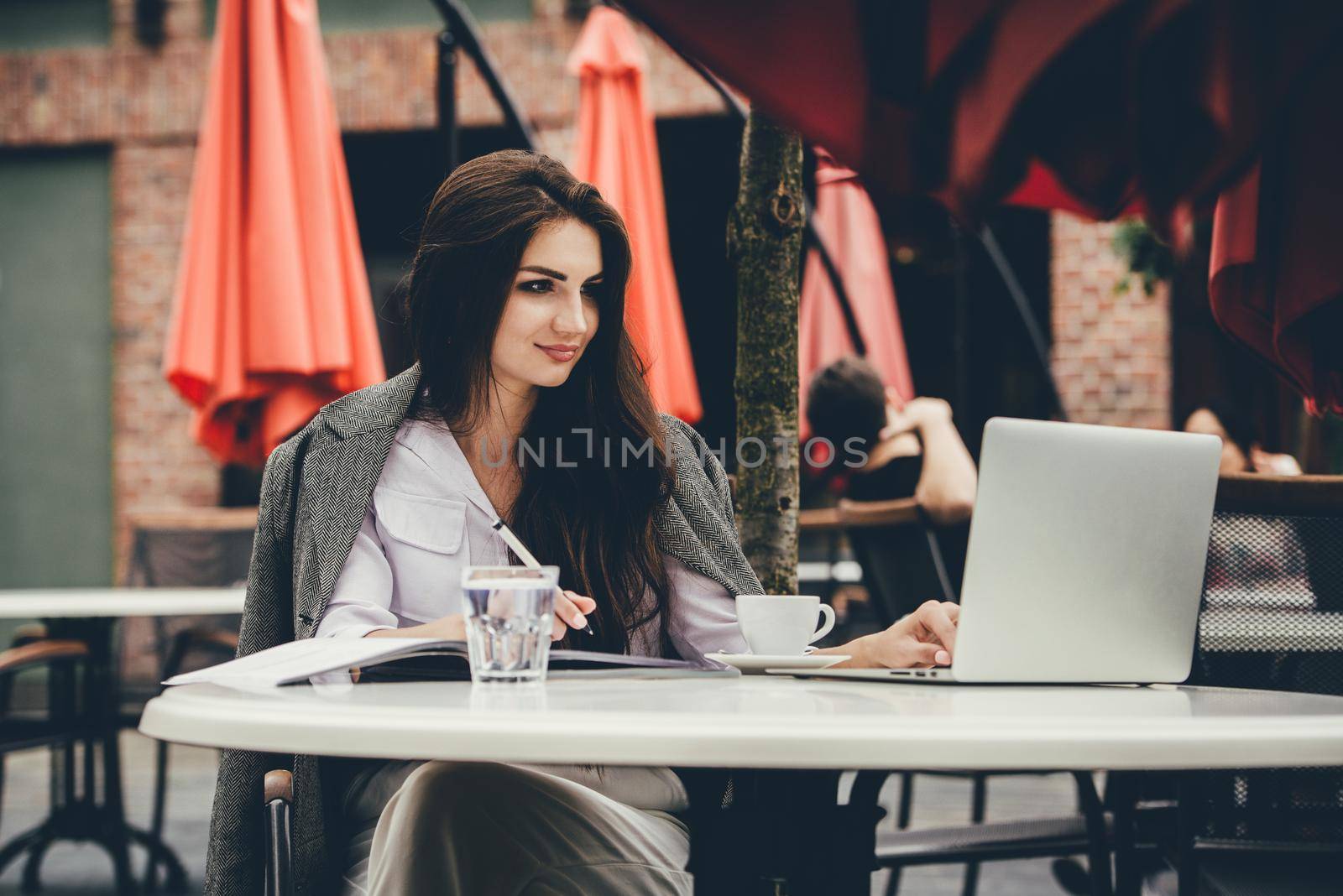 Young brunette woman using laptop computer sitting at cafe table and drik coffe. . Business People Concept