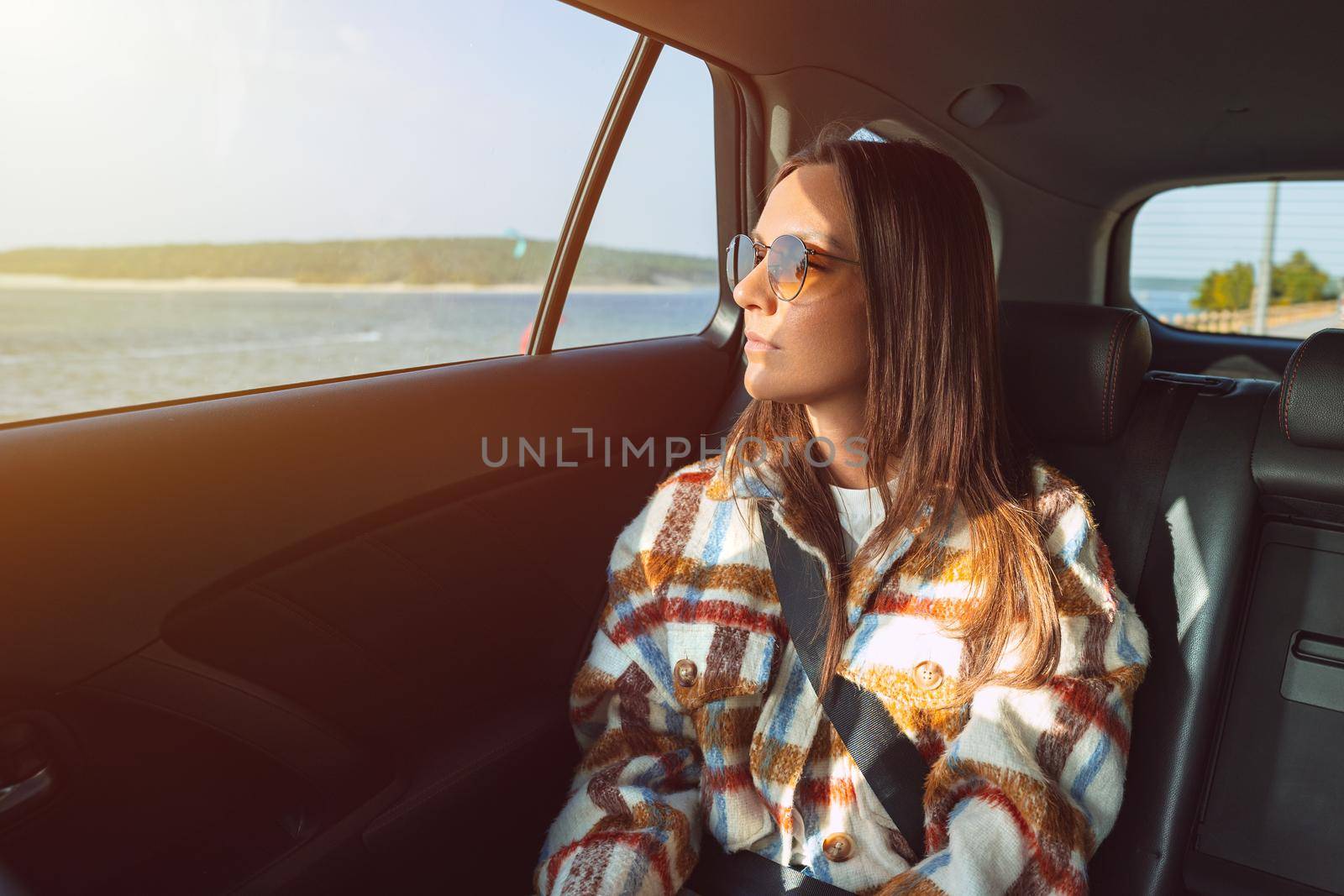 Stylish young woman sitting on back seat in the taxi car and looking through the window by DariaKulkova