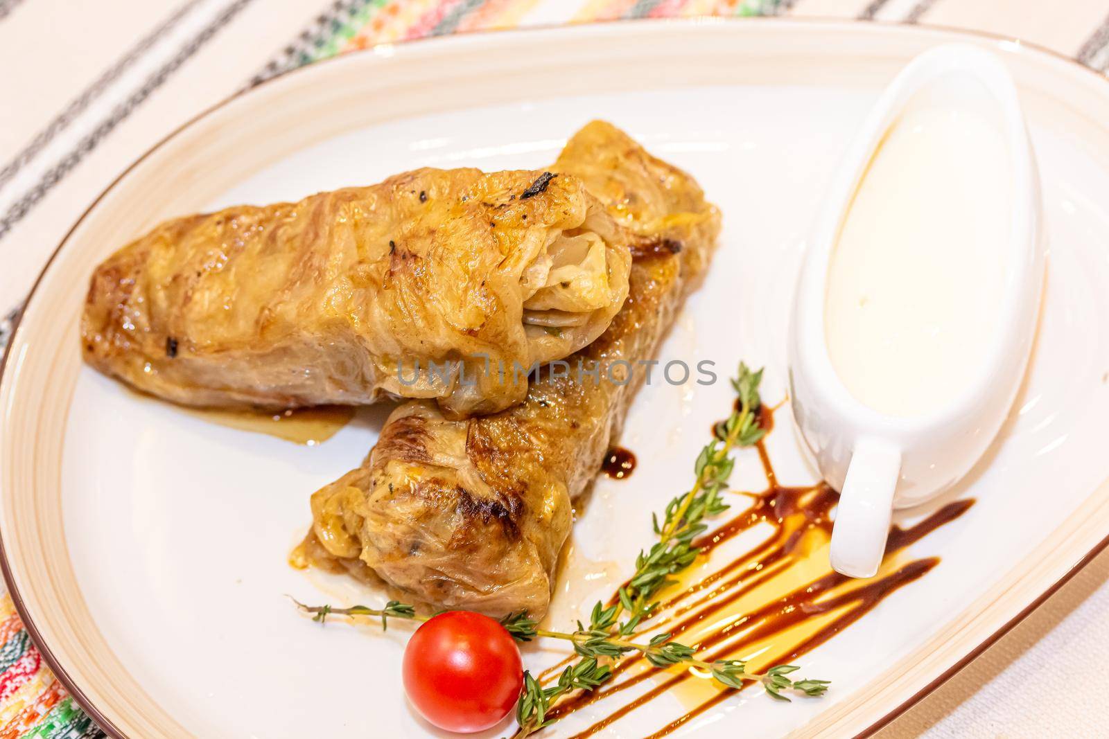 Stuffed cabbage rolls with meat on a plate with sour cream by Milanchikov