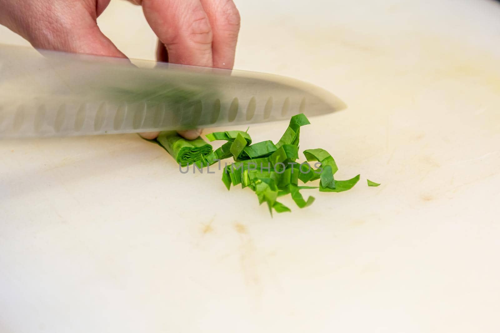 The cook very quickly cuts parsley leaves rolled into a tube by Milanchikov