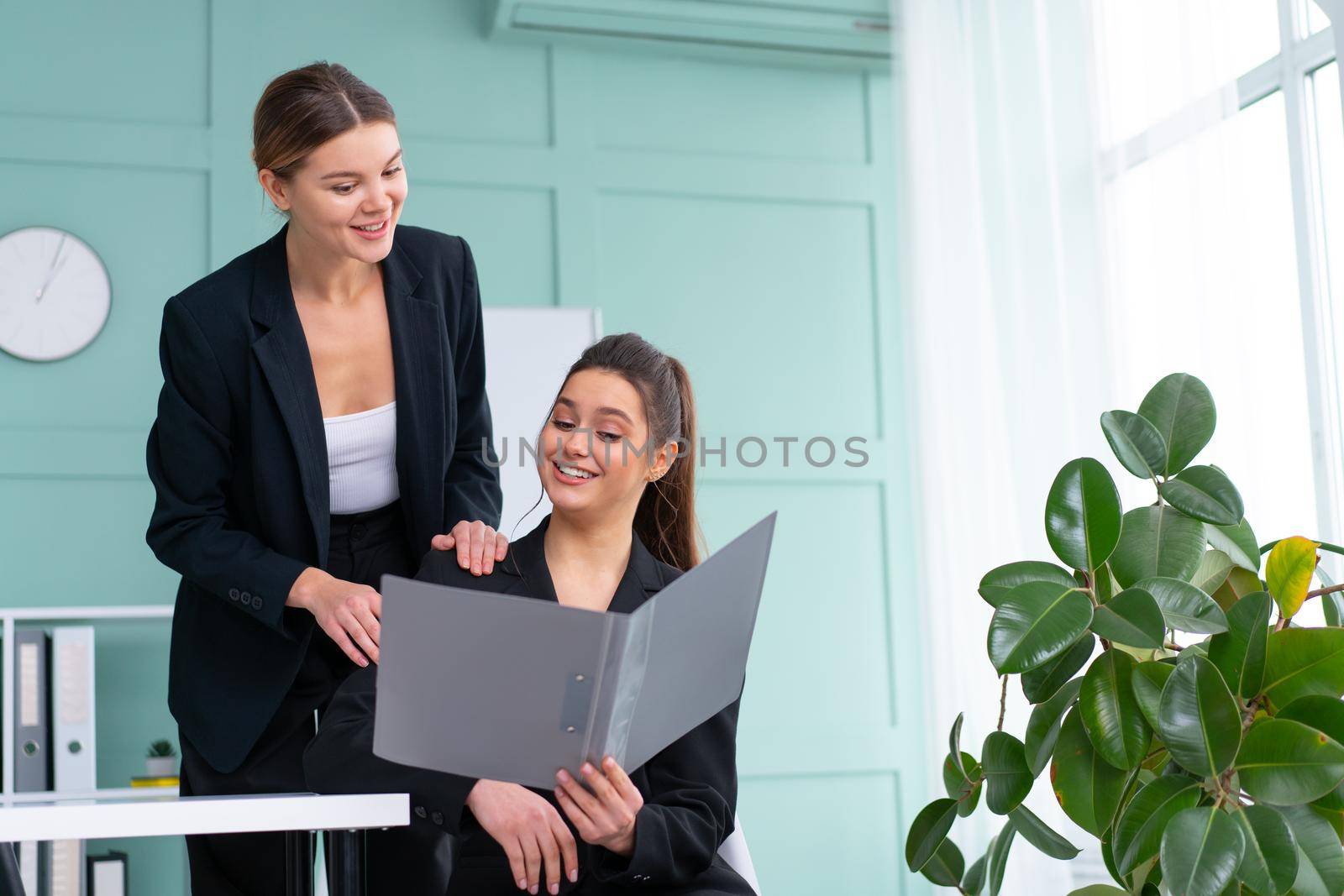 Young women leaders are checking financial statements from paper documents. Two female confident business worker dressed black suit in office checking financial document by andreonegin