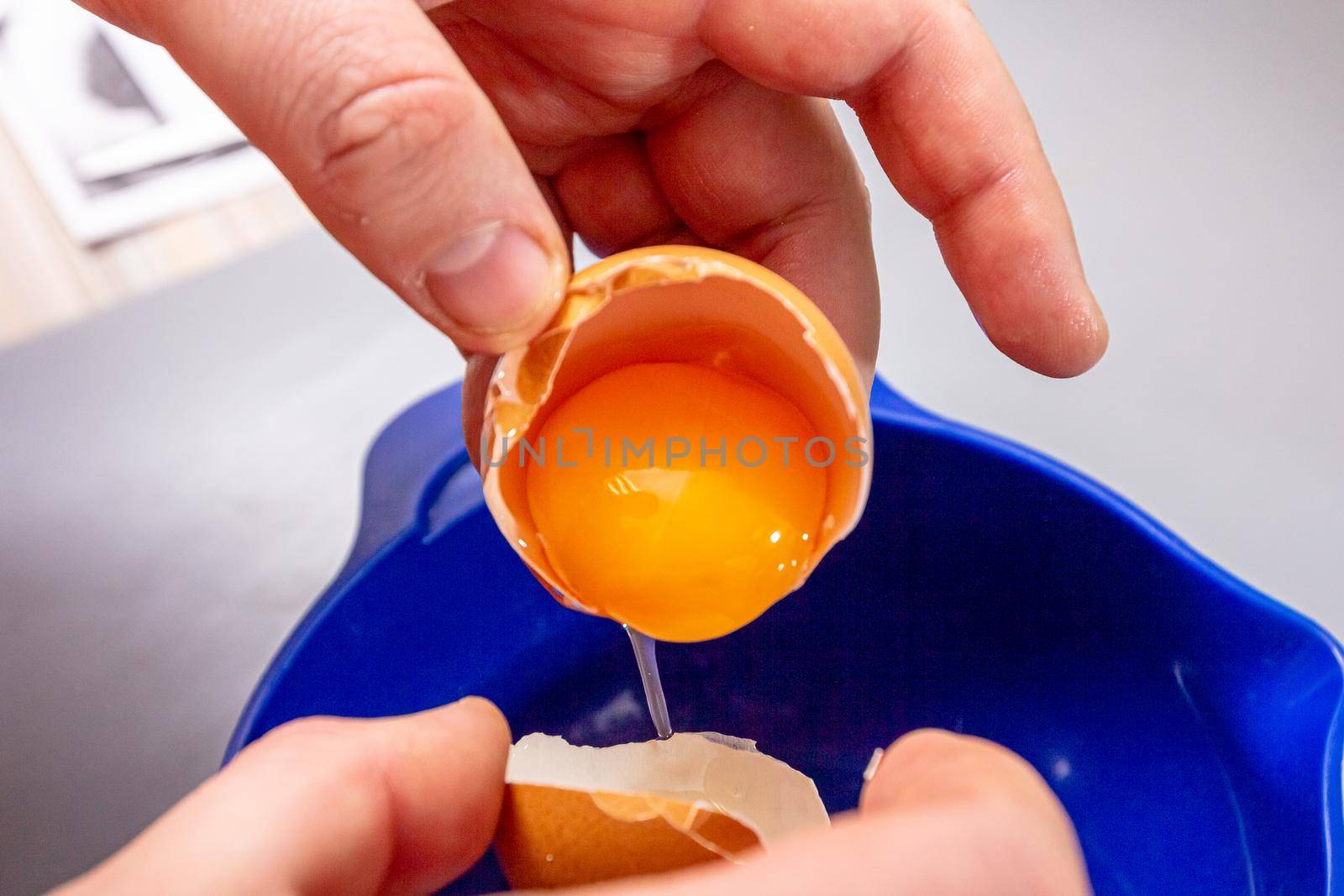 The cook separates the egg yolk from the egg white in the shell.