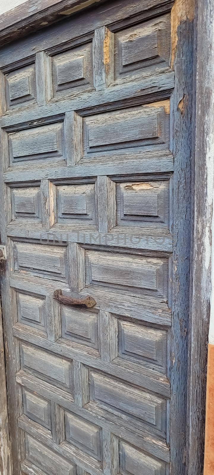 An old wooden door with traces of old paint and a rusty handle