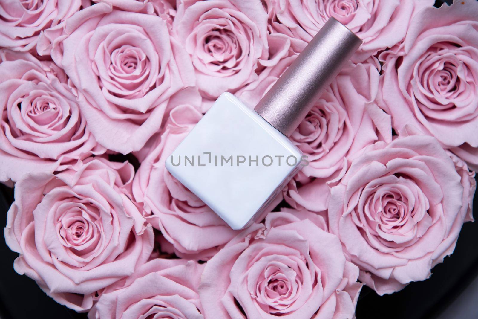 Nail polish bottle with white mockup for text lies on pink roses, background, by KaterinaDalemans