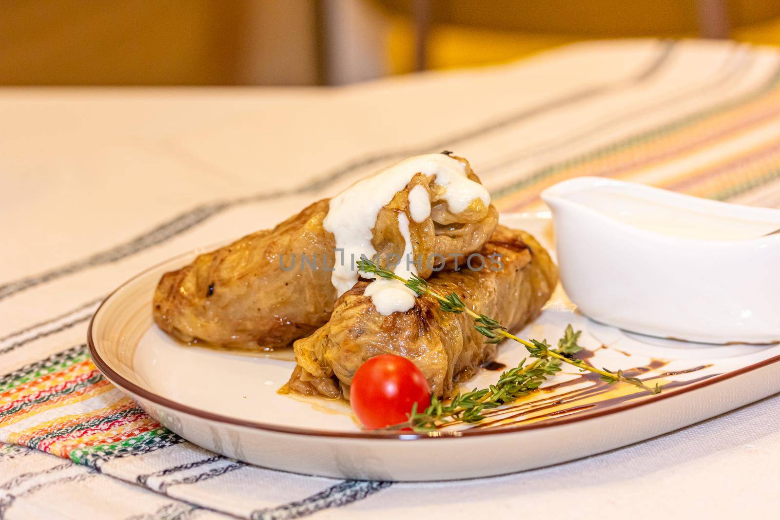 Stuffed cabbage rolls with meat on a plate with sour cream.
