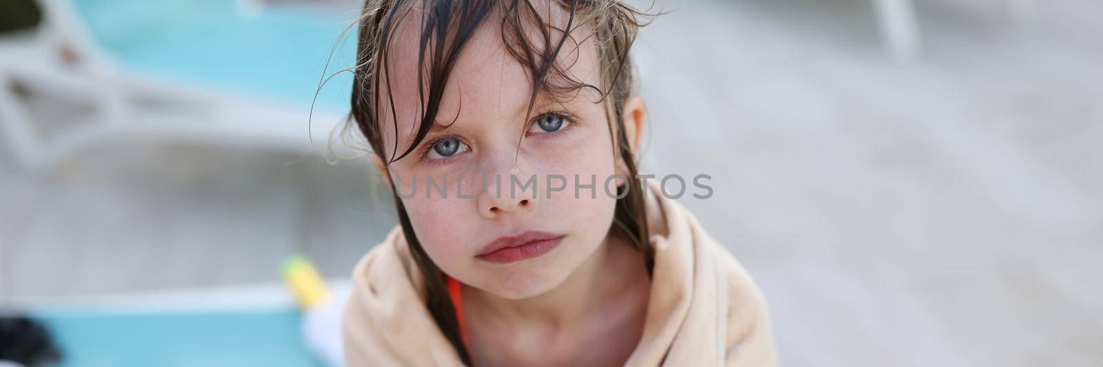 Little frozen girl in towel standing near swimming pool by kuprevich