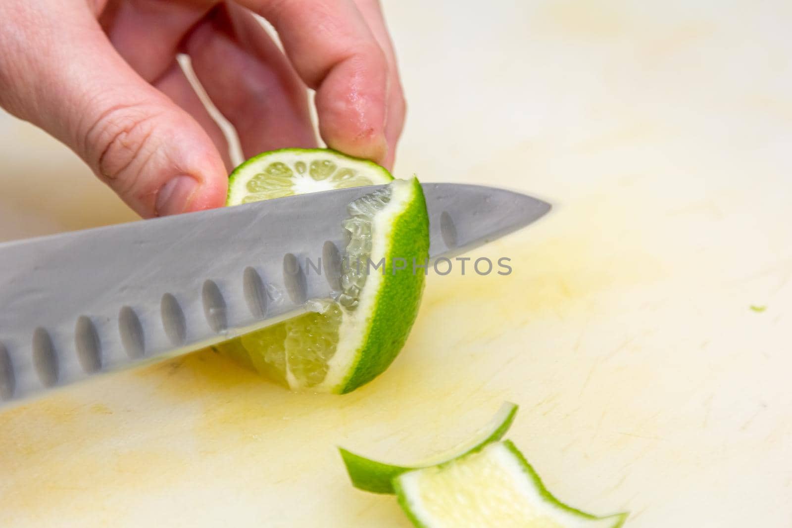 The chef cuts the skin from the lime with a knife on a white board in the restaurant
