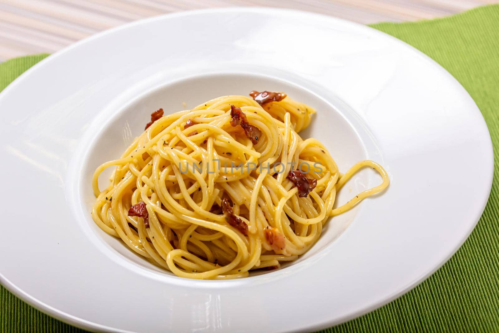 Italian delicious spaghetti carbonara pasta with bacon parmesan lies in a plate by Milanchikov