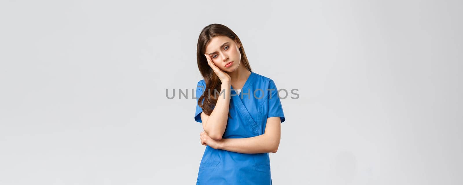 Healthcare workers, prevent virus, insurance and medicine concept. Exhausted and sleepy female nurse, doctor in scrubs, lean on palm look tired, feel fatigue from night shift at hospital.