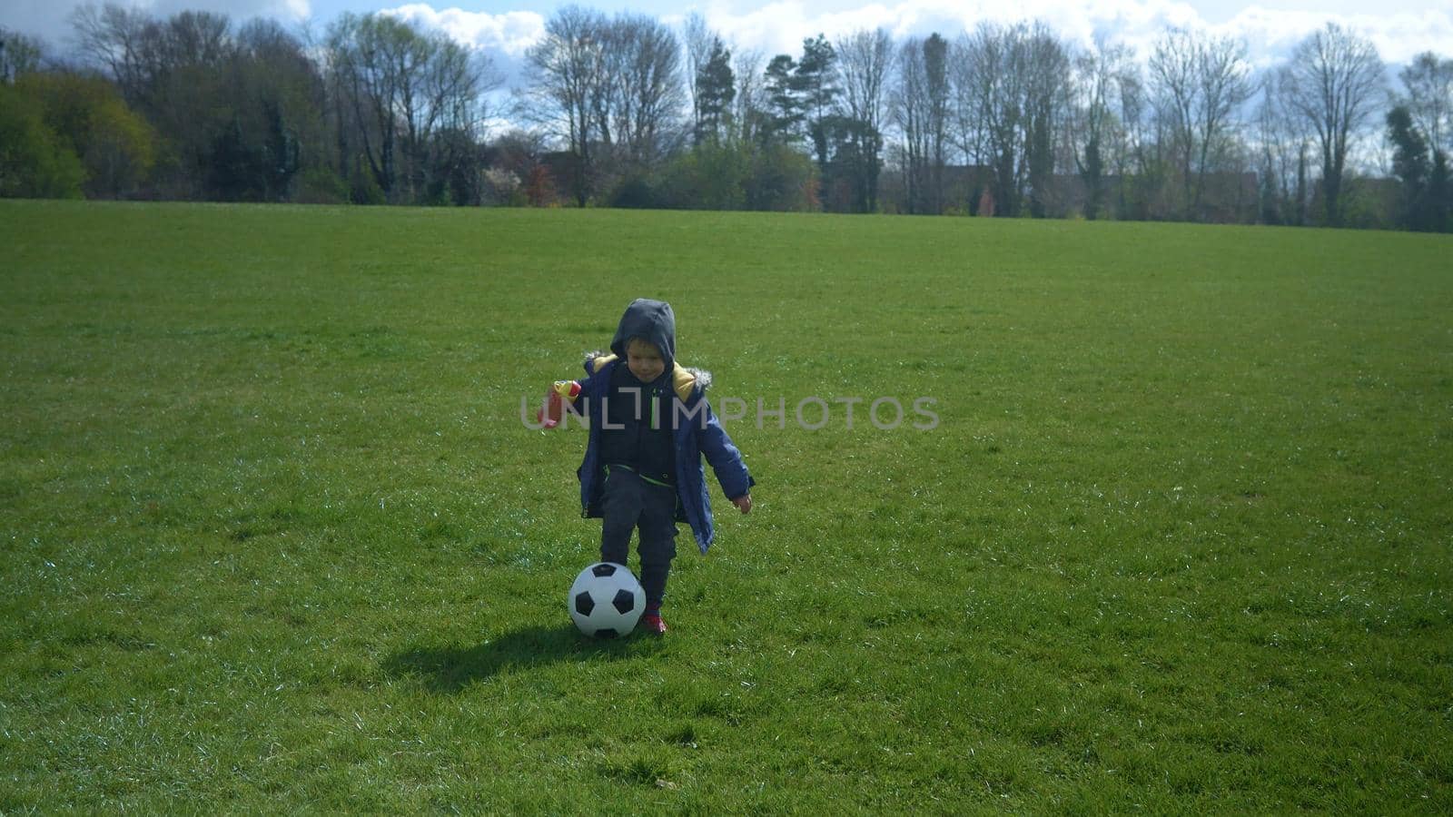 Happy Family Of Children Having Fun In Spring Park. Little Kid Run. Child Boy Dribbles Black White Classic Soccer Ball On Green Grass. People Playing Football. Childhood, Sport, Championship Concept.