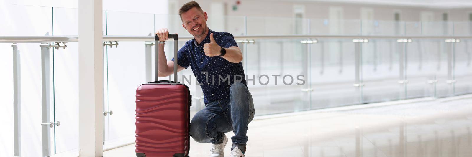 Man with suitcases showing ok gesture in hotel corridor by kuprevich