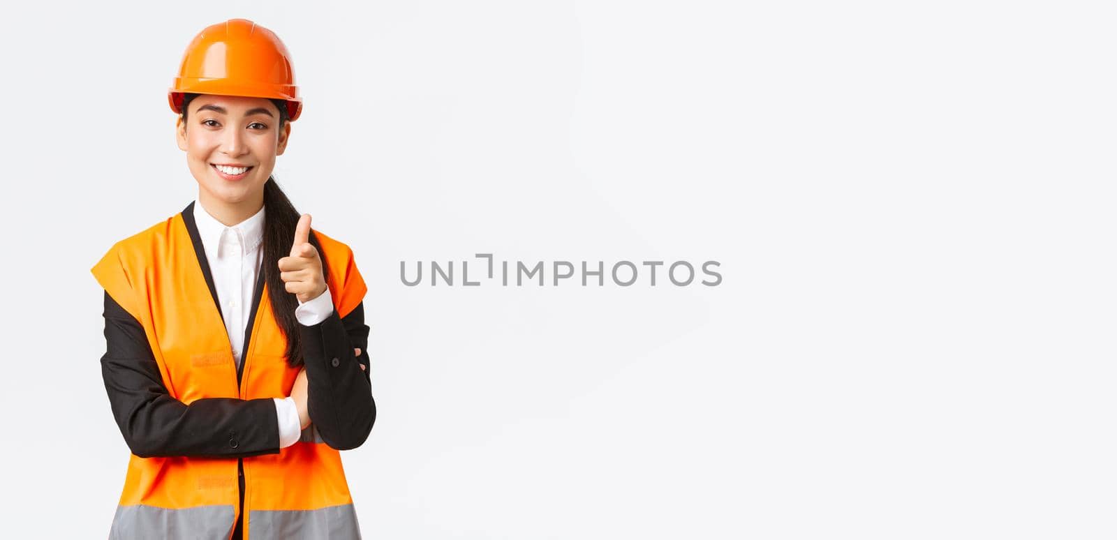 Successful and confident smiling asian female architect pointing finger at camera, wearing safety helmet and reflective jacket, introduce construction project, industrial woman inviting clients by Benzoix