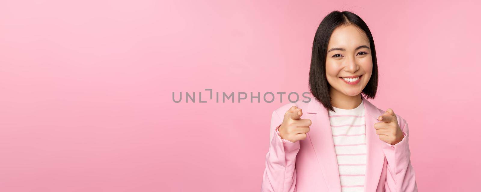 Its you, congrats. Smiling enthusiastic korean corporate lady, businesswoman pointing fingers at camera congratulating, praising you, standing over pink background.