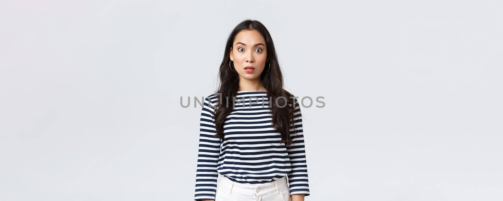 Lifestyle, people emotions and casual concept. Shocked and startled asian woman open mouth, widen eyes at camera when find out terrible concerning news, stand stupor white background.