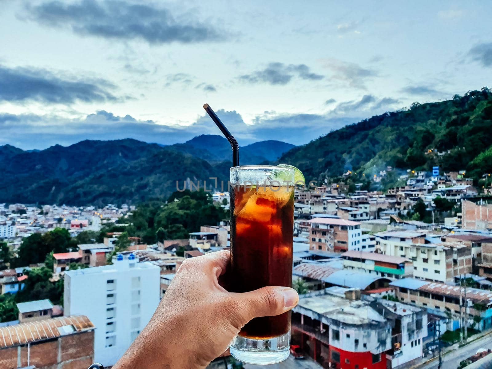 Hand of a man with a drink with the view of the city of Chanchamayo located in the department of Junin in Peru. by Peruphotoart