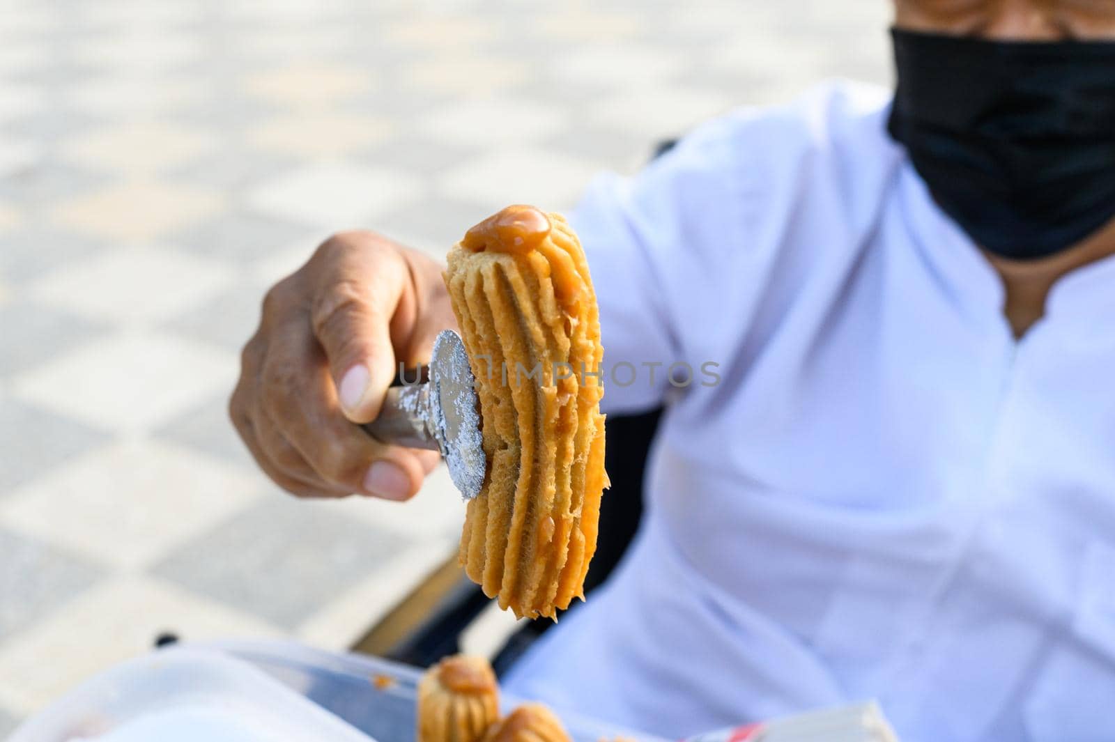 Unrecognizable seller of Peruvian churros, an exquisite dessert filled with blancmange. by Peruphotoart