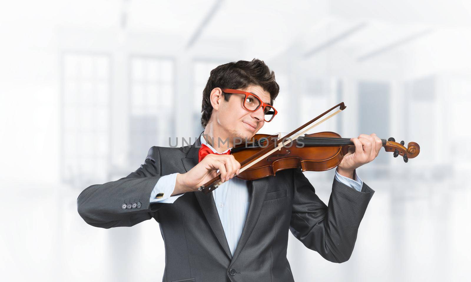 Young musician with glasses plays the violin. Smiles and enjoys